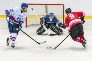 Ice hockey goalkeeper trying to catch puck in ice hockey stadium.